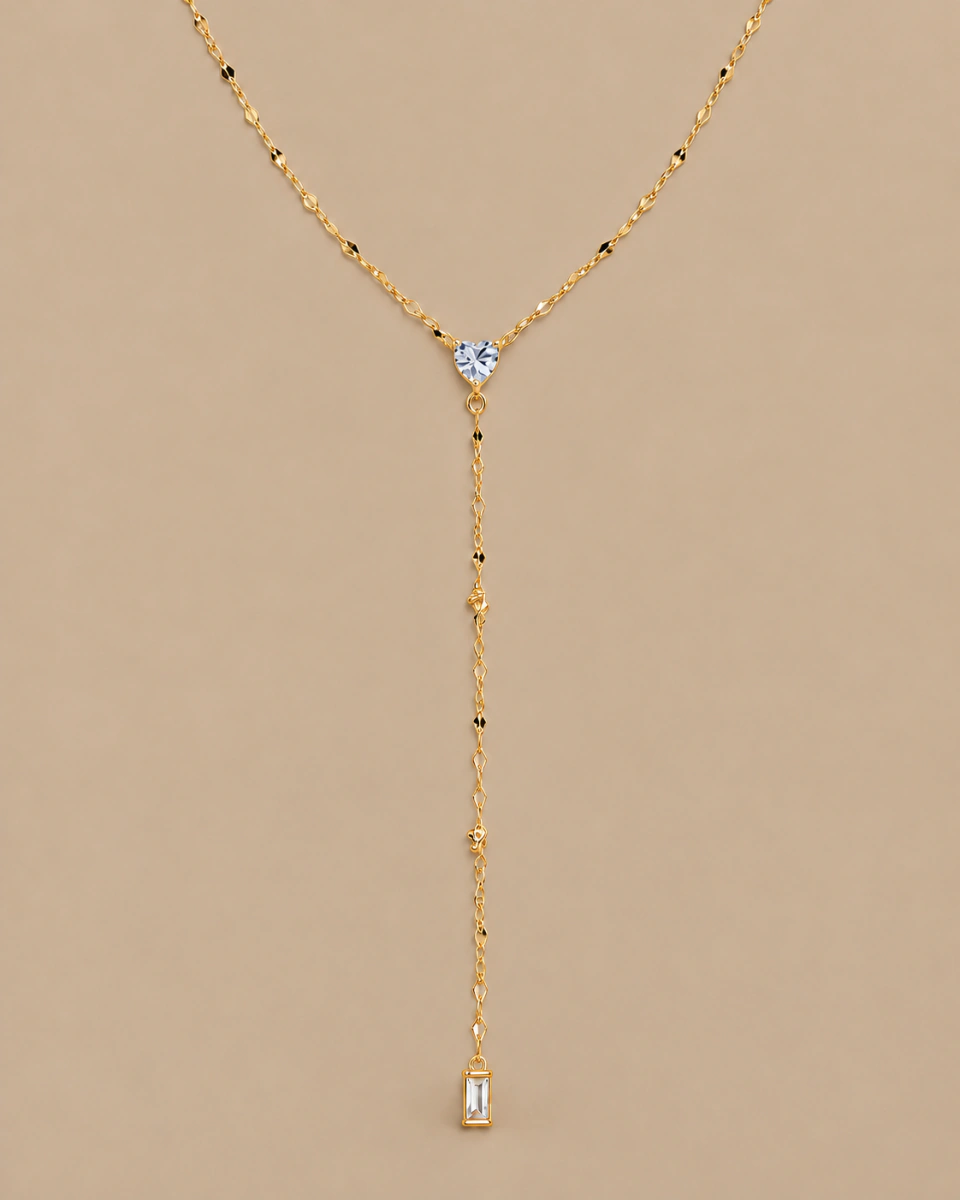 The clear-heart lariat with its complete chain drop, on a warm beige background