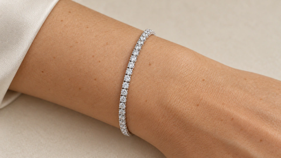 The clear tennis bracelet worn on a wrist beside an ivory sleeve