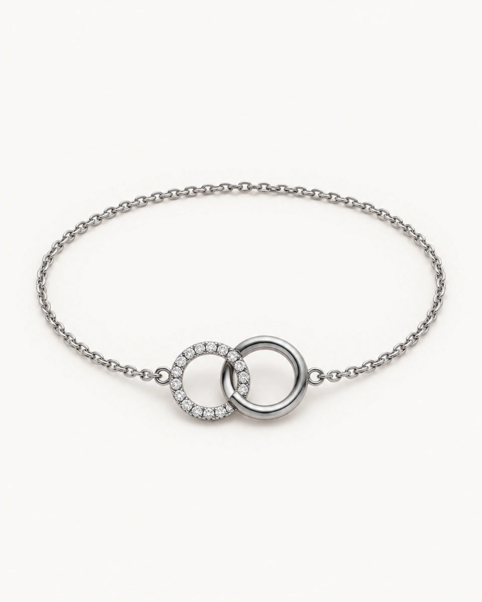 The silver-tone circle bracelet with two interlocked circles, one smooth and one set with clear stones, on a light background