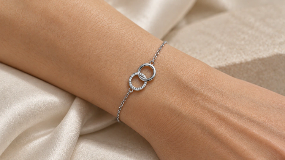 The silver-tone circle bracelet worn on a wrist against ivory fabric